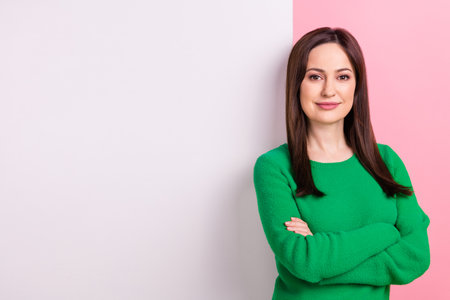 Photo of pretty cheerful woman wear green sweater arms crossed poster emtpy space isolated pink color backgroundの写真素材