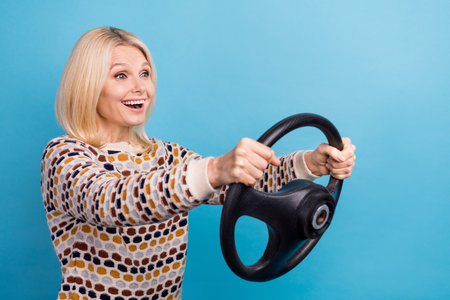 Photo of pretty excited girl wear sweater riding vehicle looking empty space isolated blue color backgroundの写真素材