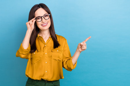 Photo of cheerful mature age business lady touch spectacles glasses pointing finger empty space proposition ad isolated on blue color backgroundの写真素材