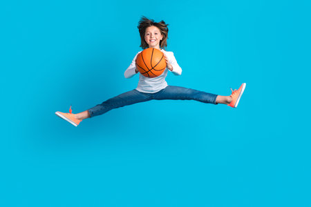 Full size photo of adorable energetic girl wear white long sleeve trousers jumping with basketball...