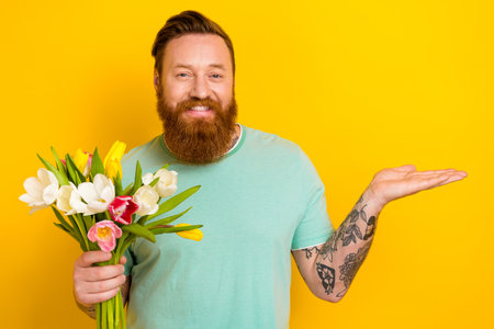 Photo of positive glad attractive gentleman wear green stylish clothes demonstrate empty space isolated on yellow color backgroundの写真素材