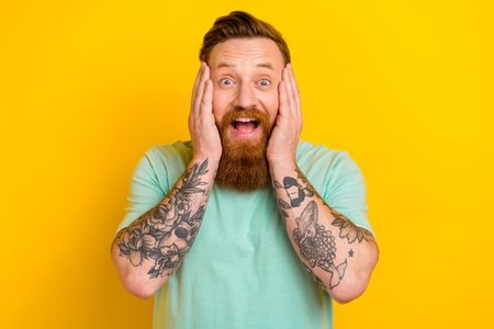 Portrait of astonished cheerful positive man open mouth impressed low prices interesting good news isolated on yellow color backgroundの写真素材