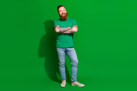 Full length photo of confident cool man wear t-shirt arms crossed looking empty space isolated green color backgroundの写真素材