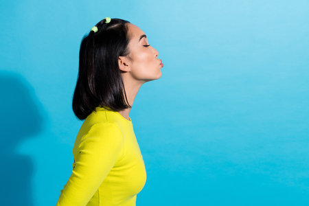 Profile photo of young korean girlfriend wear yellow top closed eyes flirt kiss imagination empty space partner isolated on blue color backgroundの写真素材