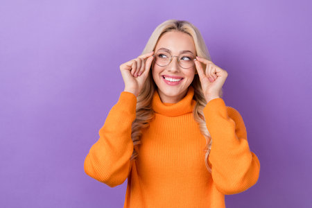 Photo of gorgeous intelligent girl with stylish hairdo orange sweater touch glasses look empty space isolated on purple color backgroundの写真素材