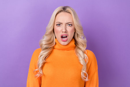 Photo of angry furious irritated girl with stylish hairdo dressed orange sweater loud shout yell isolated on purple color backgroundの写真素材