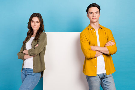 Photo of two confident business partners crossed arms wear stylish casual clothes advert white poster empty space isolated on blue color backgroundの写真素材