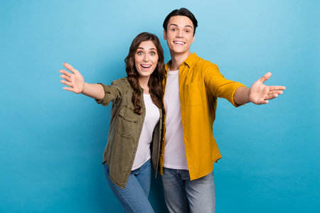 Photo of two friendly couple love story funny guy girlfriend meeting you congratulate welcome people inviting isolated on blue color backgroundの写真素材