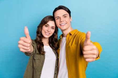 Photo of pretty cheerful husband wife dressed shirts showing you thumbs up isolated blue color backgroundの写真素材