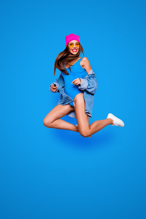 Vertical full size length body studio photo portrait of cheerful attractive pretty rejoicing confident funny fancy girl jumping up isolated bright color vivid shinny backgroundの写真素材
