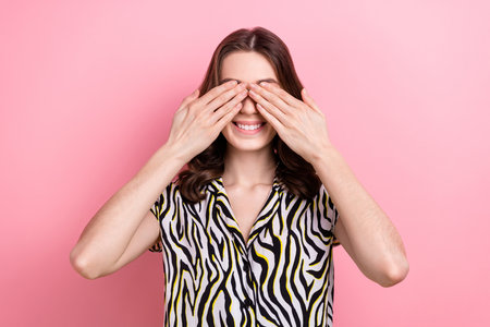 Photo of satisfied playful lady arms covering eyes beaming smile play hide-and-seek isolated on pink color backgroundの写真素材