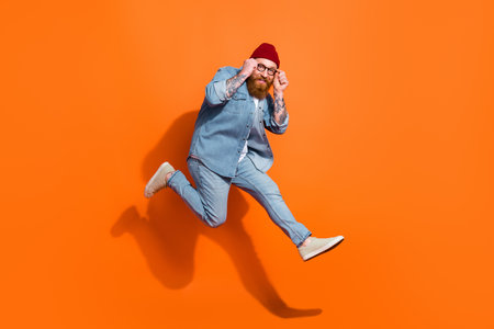 Full size photo of overjoyed nice person jumping arms touch glasses isolated on orange color backgroundの写真素材