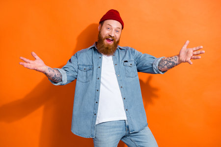 Portrait of cheerful satisfied person raise arms open mouth have good mood isolated on orange color backgroundの写真素材