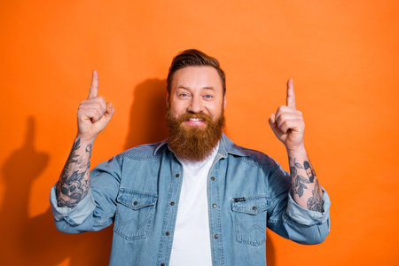 Portrait photo of smiling handsome red hair business man hr manager company direct fingers mockup new vacancy isolated on orange color backgroundの写真素材