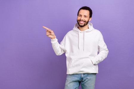 Portrait of positive person indicate finger empty space ad proposition isolated on purple color backgroundの写真素材