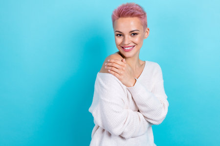 Photo of adorable gorgeous lady hand naked shoulder wear white stylish pullover stand empty space isolated on blue color backgroundの写真素材