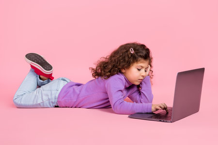 Full length photo of charming sweet little child dressed purple pullover typing email modern device isolated pink color backgroundの写真素材