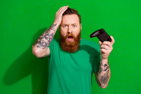Photo of impressed unlucky man wear t-shirt loosing game isolated green color background