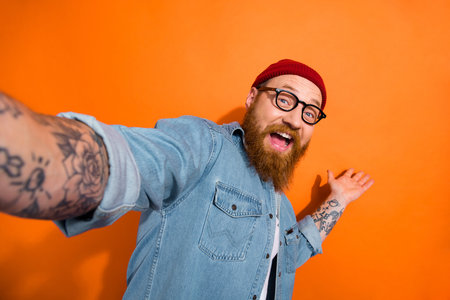 Portrait of positive cheerful guy making selfie video recording demonstrate product isolated on shine color backgroundの写真素材