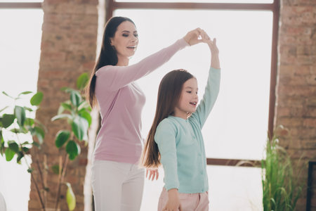 Photo of cute good mood daughter mom dressed casual clothes having fun dancing indoors apartment roomの写真素材