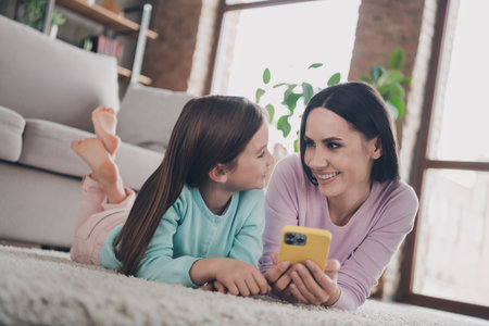 Photo of adorable cute mother daughter wear casual outfits chatting  modern device indoors house roomの写真素材