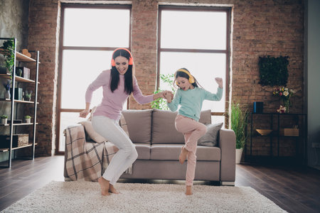Photo of sweet cheerful mother daughter wear casual outfits listening songs having fun together indoors house roomの写真素材