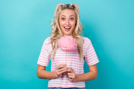 Photo of lovely astonished person hands hold cotton candy stick isolated on turquoise color...
