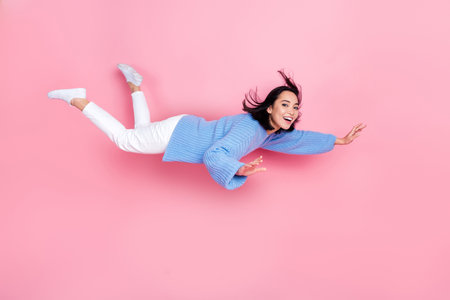 Full size profile photo of cheerful peaceful girl flying levitate isolated on pink color backgroundの写真素材