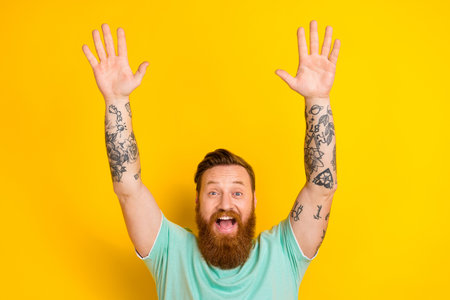 Photo of overjoyed positive glad man wear green trendy clothes have fun yes hooray isolated on yellow color backgroundの写真素材