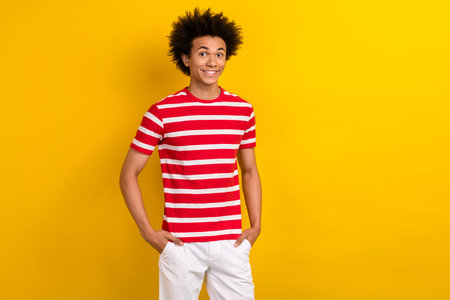 Portrait of satisfied young person put hands pockets empty space ad isolated on yellow color backgroundの写真素材