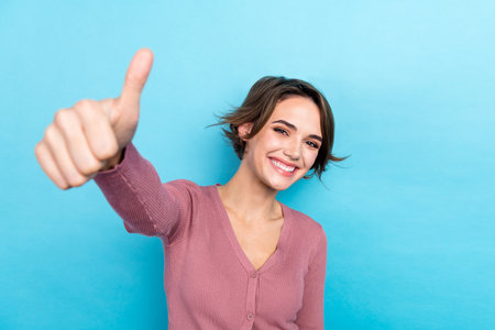 Photo of cool nice lady showing thumb up symbol directly on camera wear pink shirt outfit isolated blue color backgroundの写真素材