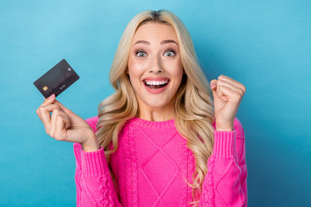 Photo of tricky lucky lady wear pink sweater rising bank card rising fist isolated blue color backgroundの写真素材