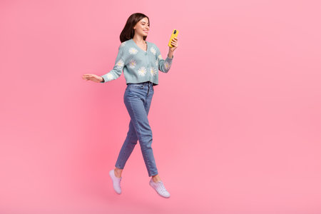Photo of young joyful pretty woman brown hair jump phone writing friends walk with her have fun...