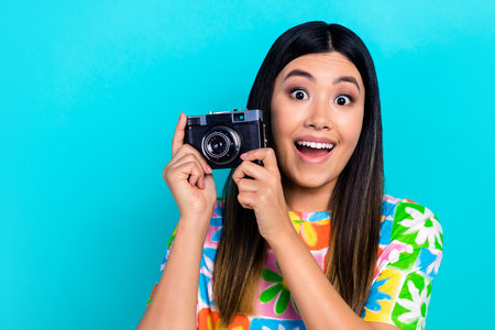 Photo of shiny impressed lady wear flower print t-shirt rising retro photo camera empty space isolated blue color backgroundの写真素材