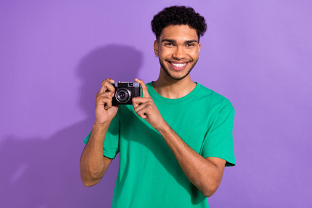Photo of funky cheerful guy dressed green t-shirt tacking photo vintage camera isolated violet color...