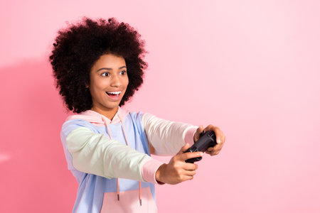 Photo of pretty excited little child dressed hoodie enjoying game empty space isolated pink color...