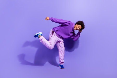 Full size photo of funny funky satisfied positive person wear violet hoodie pants dancing having fun isolated on purple color backgroundの写真素材