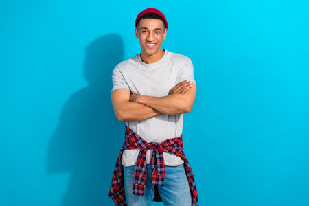 Photo of funky confident guy dressed grey t-shirt smiling arms crossed isolated blue color backgroundの写真素材