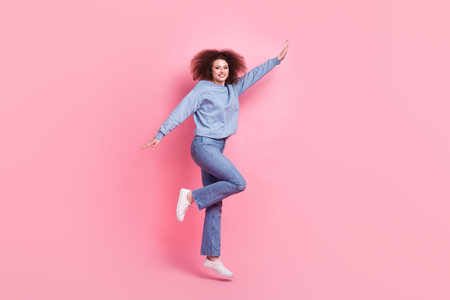 Full length photo of carefree excited woman dressed blue sweatshirt jumping high rising hands...