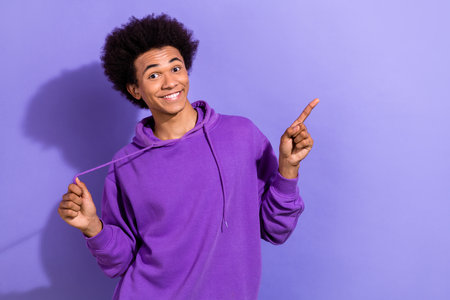Photo of positive nice man arm hold hoodie lace indicate finger empty space offer isolated on violet...