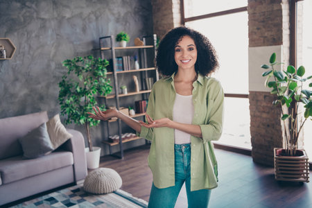 Photo of pretty positive lady real estate agent toothy smile recording video arms demonstrate new modern apartment insideの写真素材