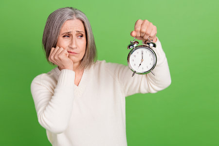 Photo of bored pensioner woman grey bob hair touch cheek looking alarm clock schedule need more...