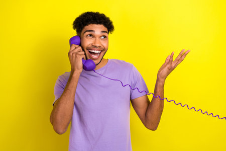 Portrait of positive overjoyed person speak communicate retro cable handset phone isolated on yellow color backgroundの写真素材