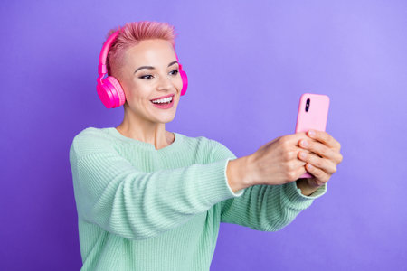 Photo of pretty cheerful lady dressed teal pullover listening songs tacking selfie modern device isolated purple color backgroundの写真素材