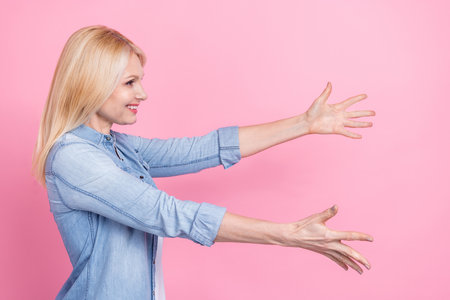 Profile photo of senior charming lady spread arms palms open hugs catch throw product object wait isolated pink color backgroundの写真素材