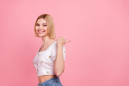Portrait of pretty young lady showing empty space new clothes collection sale prices wear white crop shirt isolated pink color backgroundの写真素材