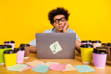 Photo of sleepy tired guy closed eyes desktop netbook coffee cup isolated on yellow color background