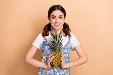 Photo of young girl funny curls ponytails wear dress presenting her favorite fruit pineapple sweet...