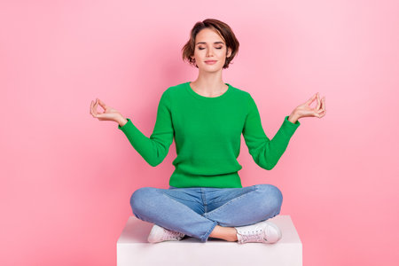 Full length photo of calm adorable girl wear trendy green clothes sitting practicing yoga relax rest isolated on pink color backgroundの写真素材