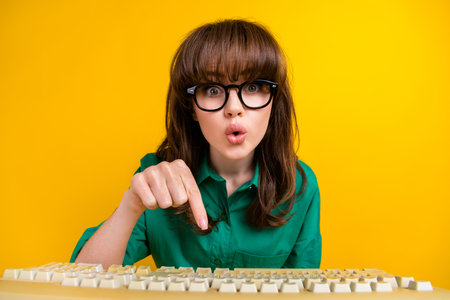 Photo of funky shocked woman dressed green shirt communicating obsolete device isolated yellow color backgroundの写真素材
